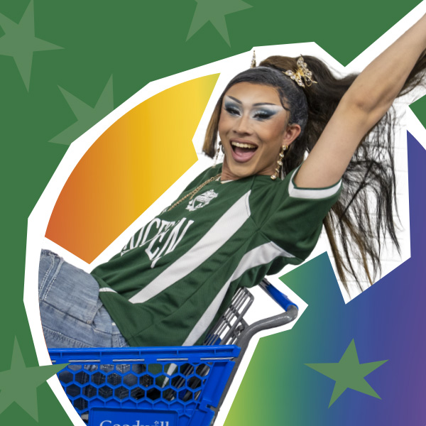Viper Fengz in a Goodwill shopping cart smiling with her arm raised. The background is green with a rainbow and light green stars.