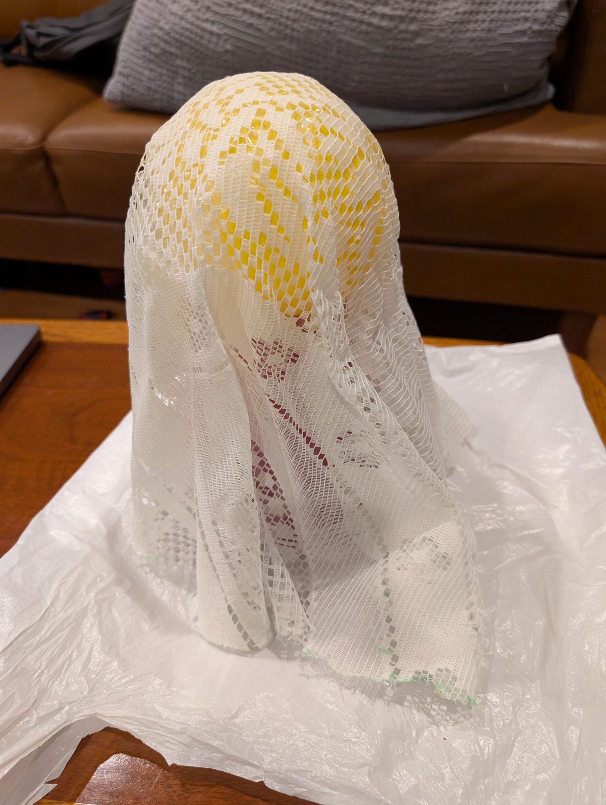 Lace fabric laid over a small yellow balloon on top of a stack of red solo cups