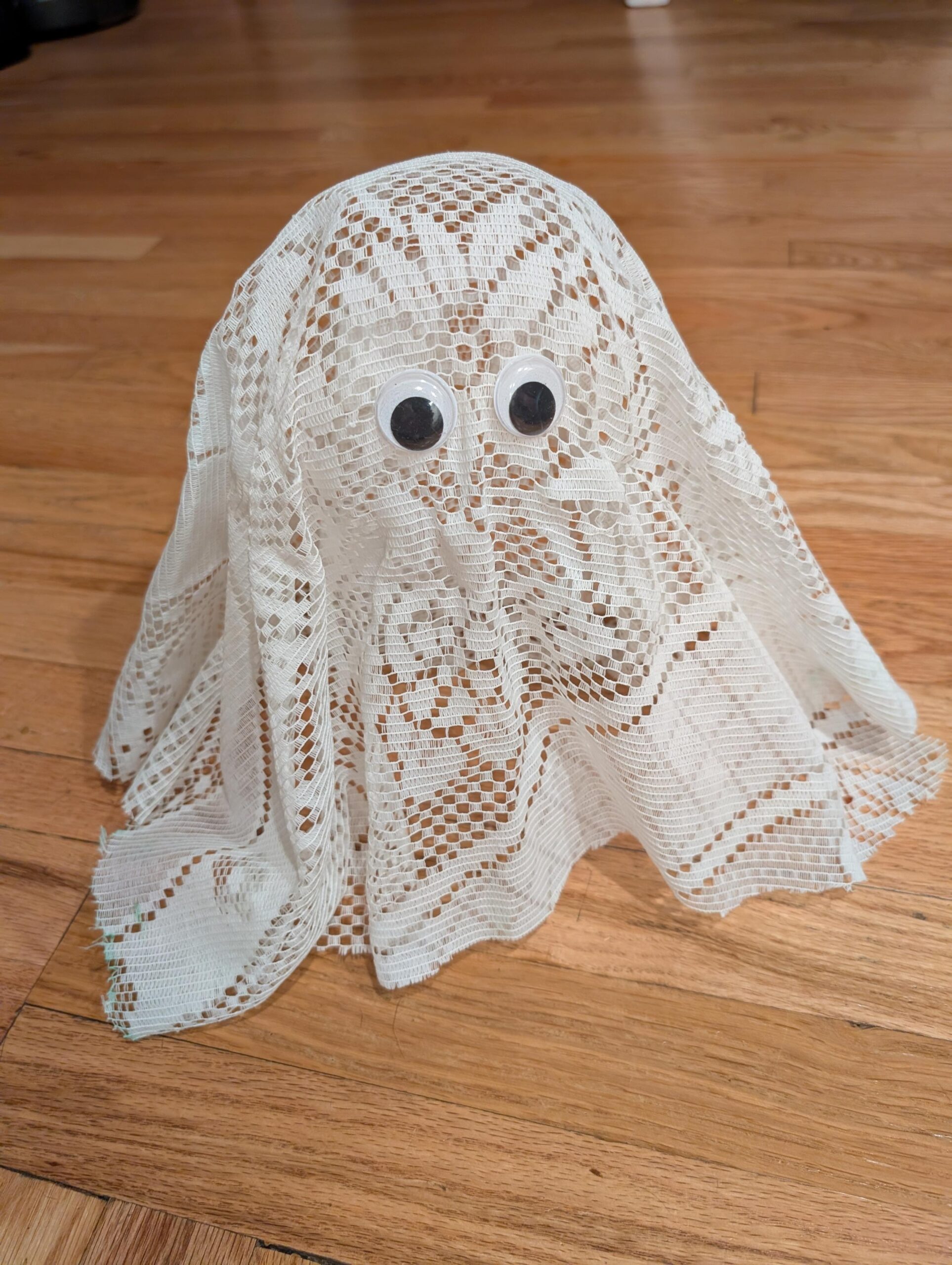 a DIY ghost decor made out of lace fabric and googly eyes