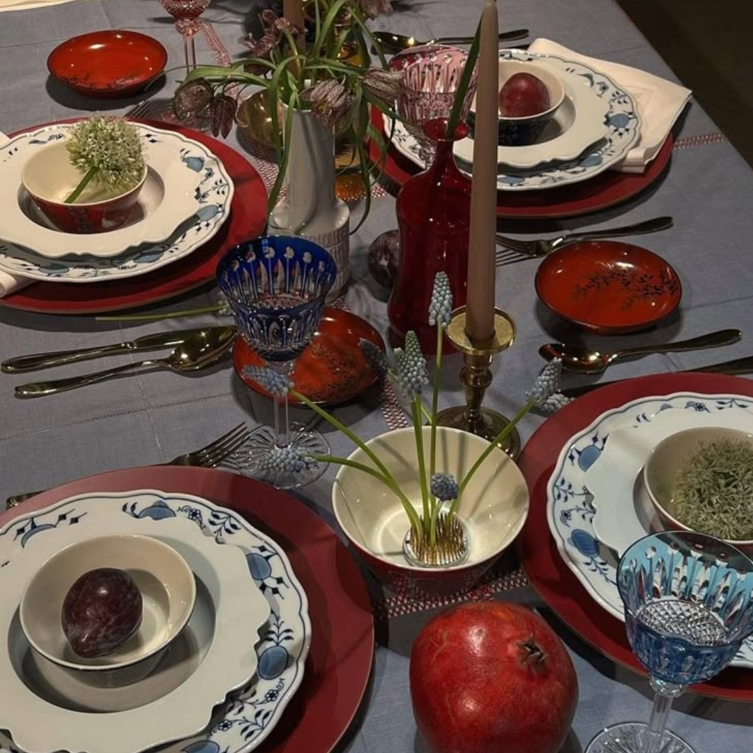 A blue, white, and red holiday tablescape. There are stacked plates, plants, and an assortment of decor items.